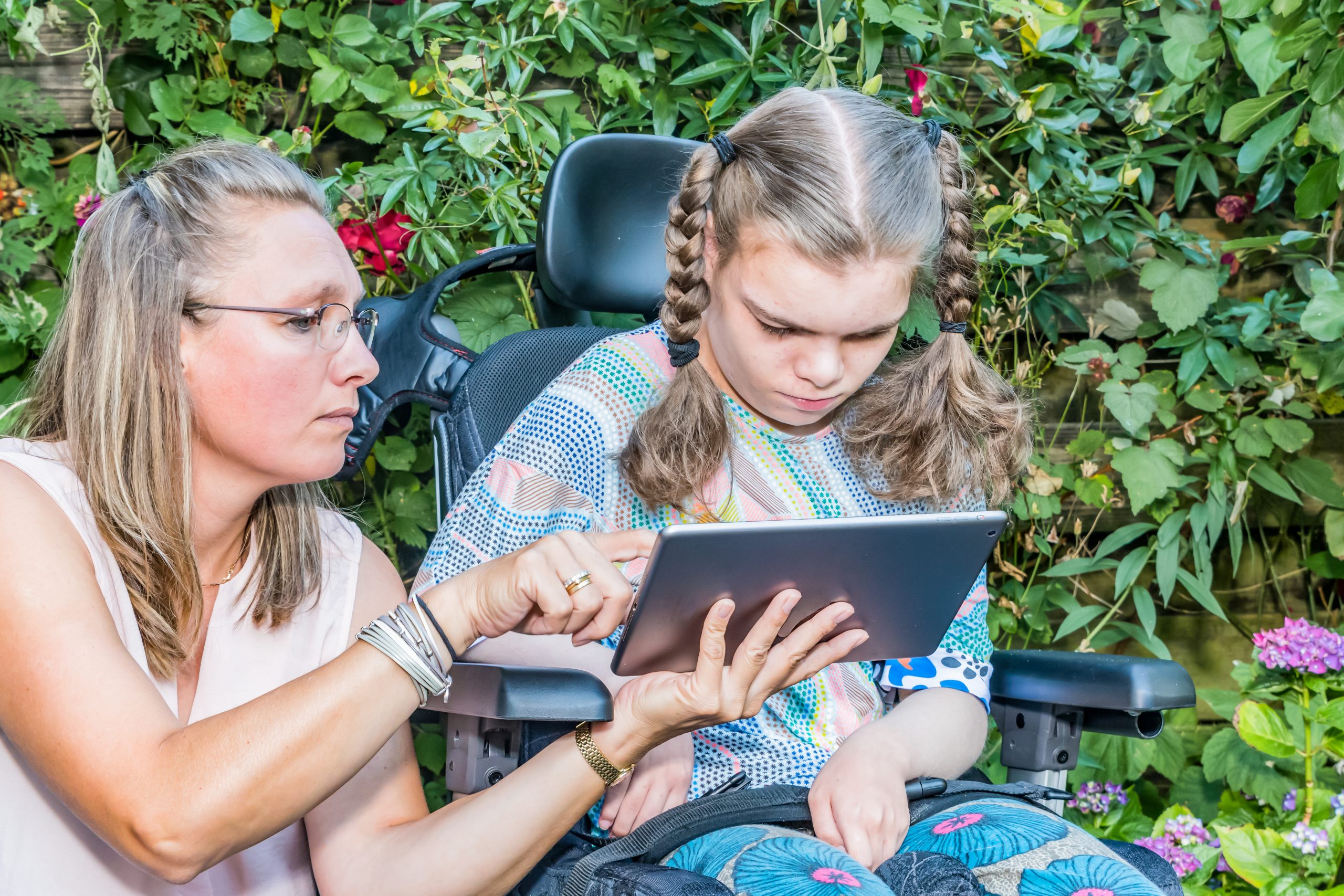 Disabled child in wheelchair receives I/DD services from a woman on tablet